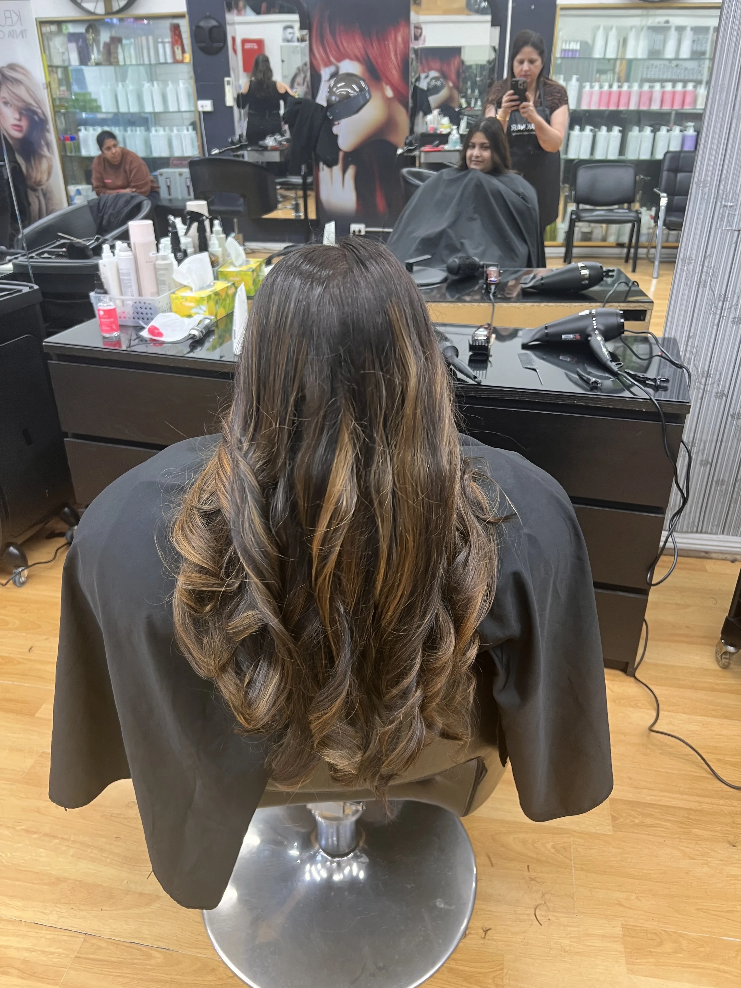 Rear view of a long balayage blow-wave with mirror stations behind