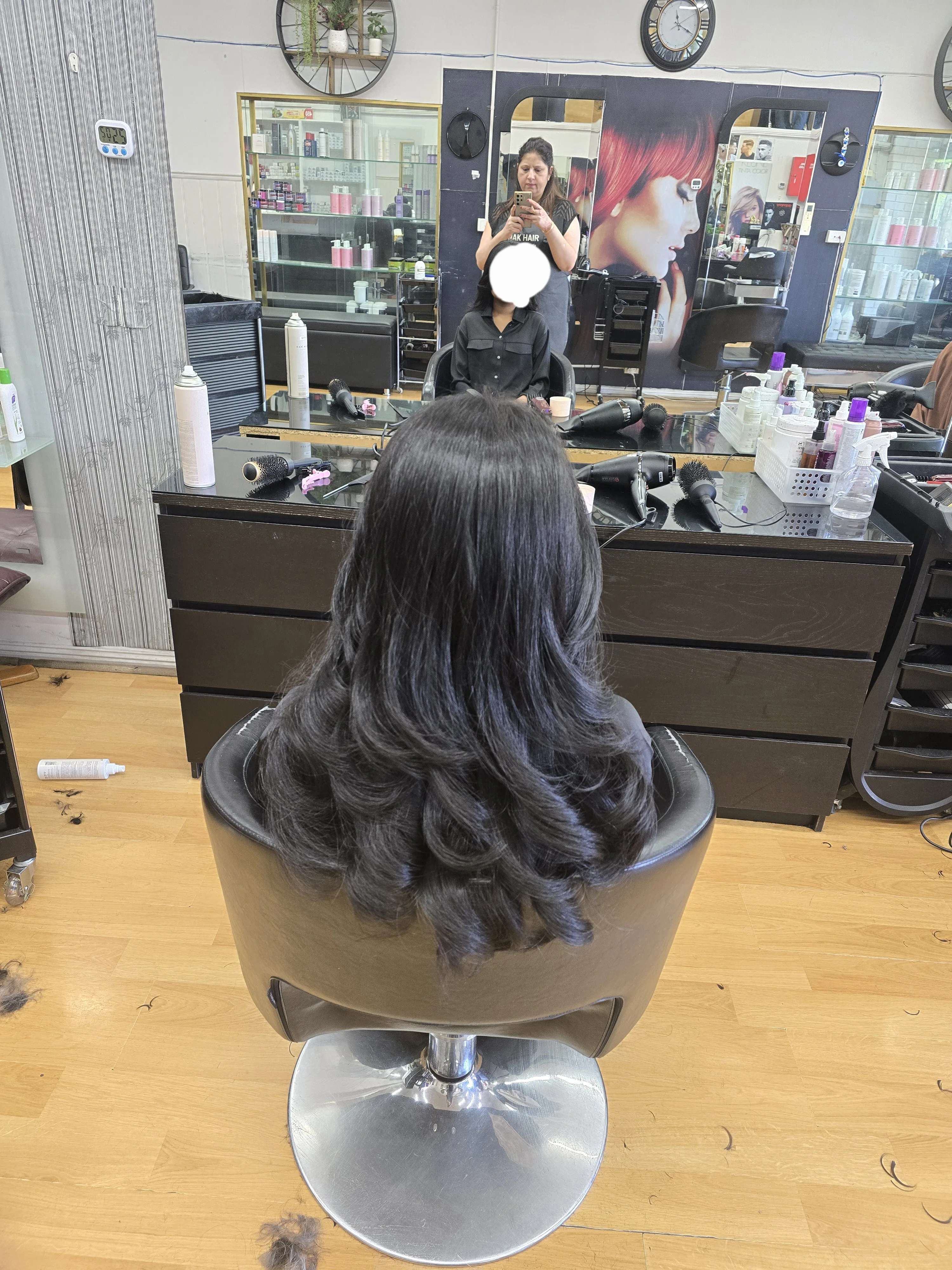Rear view of a bouncy curled blow-dry with styling stations behind