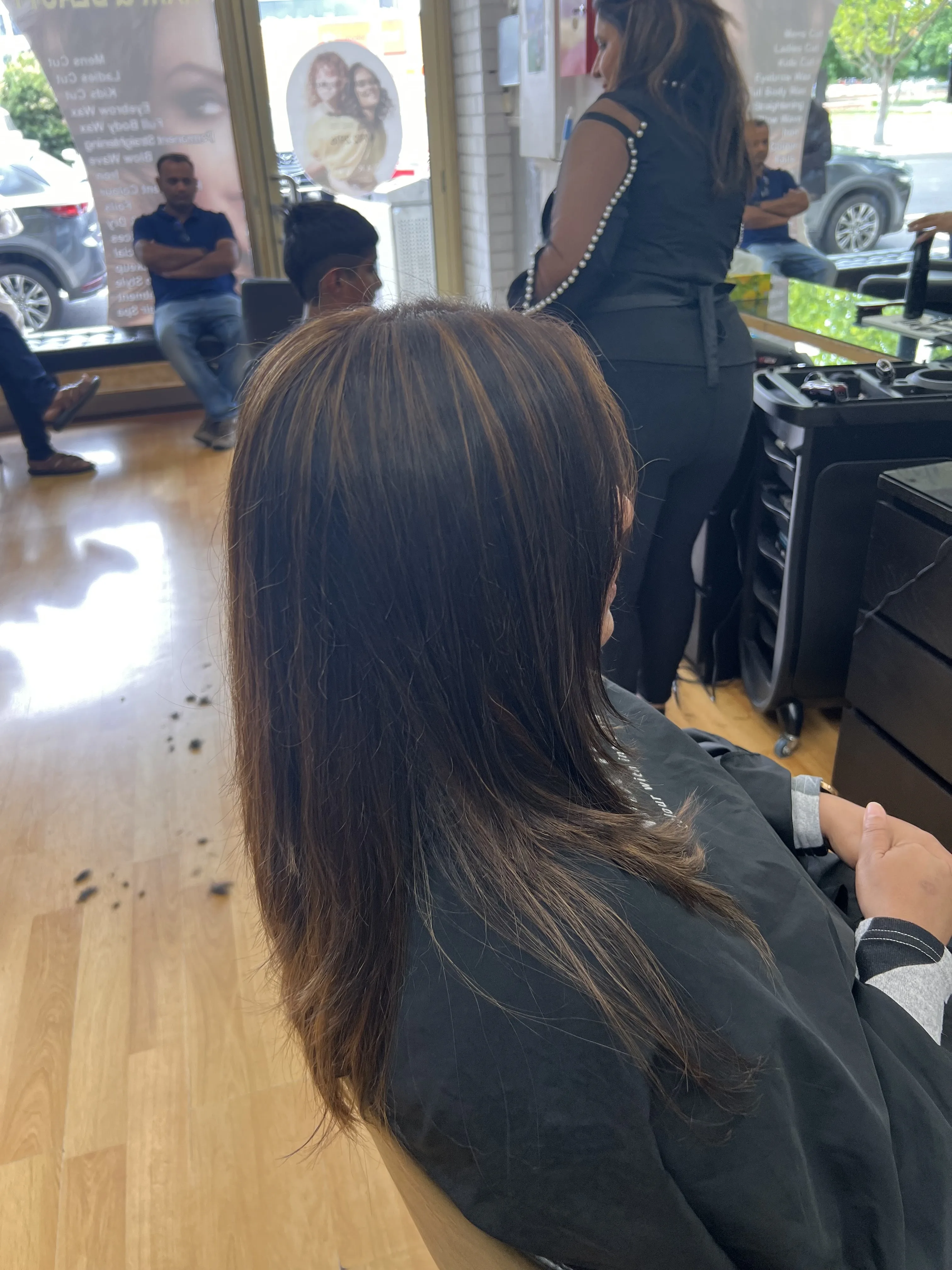 Side view of a client with highlighted lengths, staff and salon floor visible