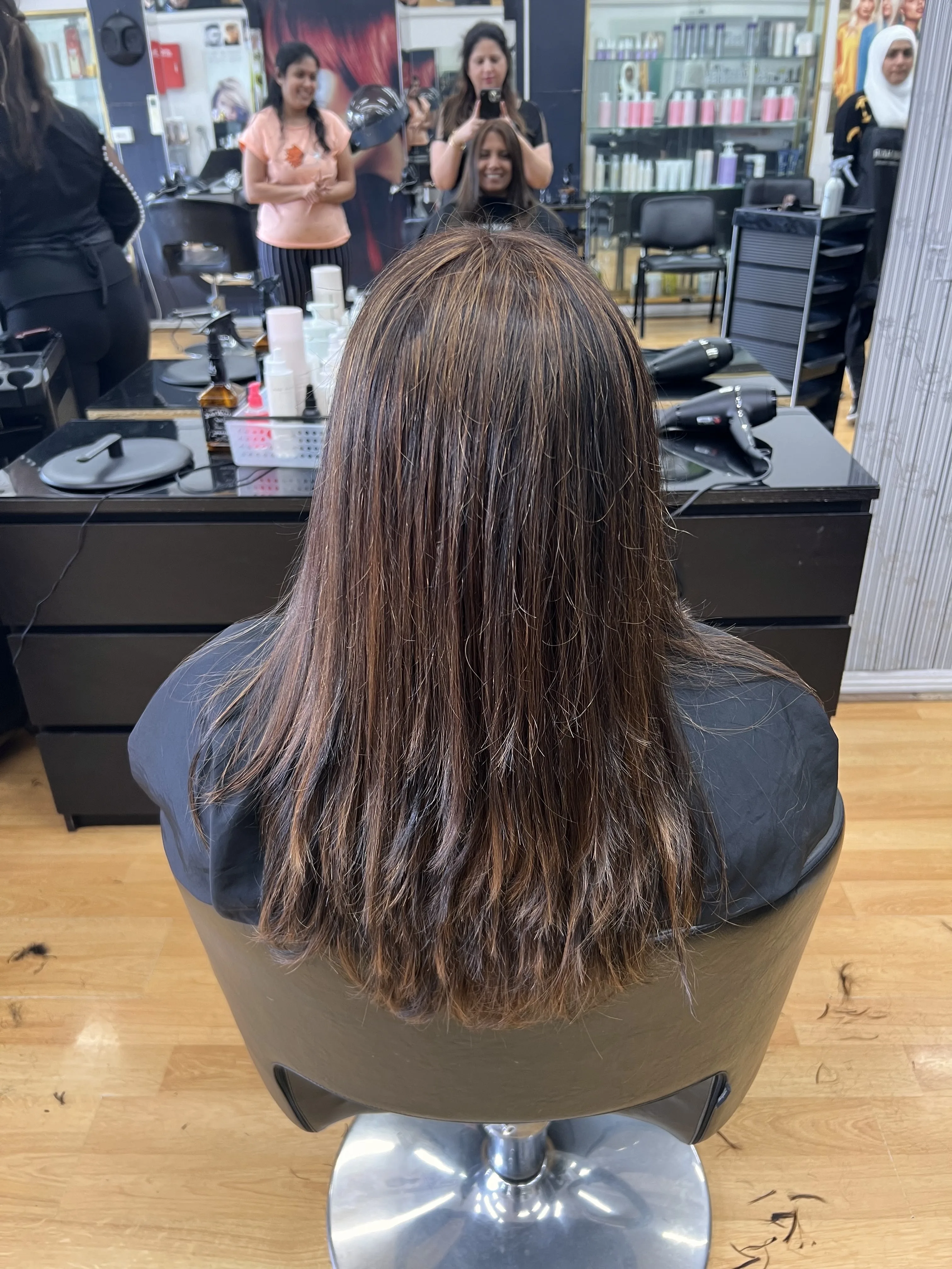 Rear view of long straight hair, staff working in the background